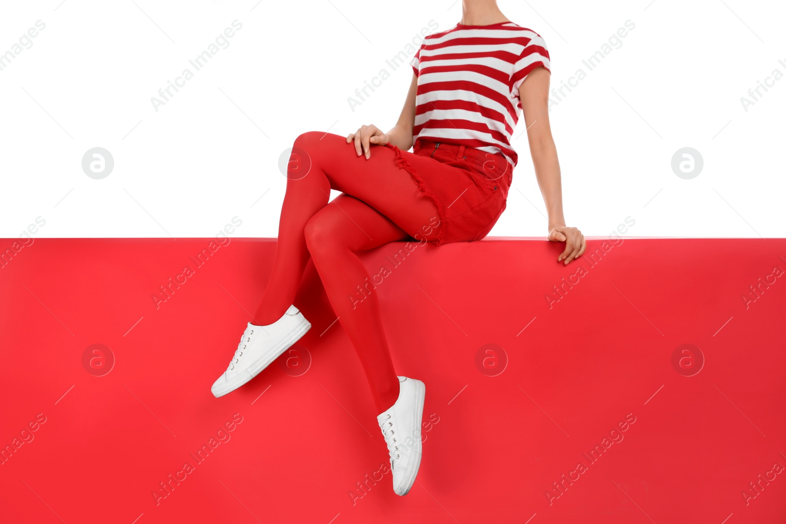 Photo of Woman wearing red tights and stylish shoes sitting on color background, closeup