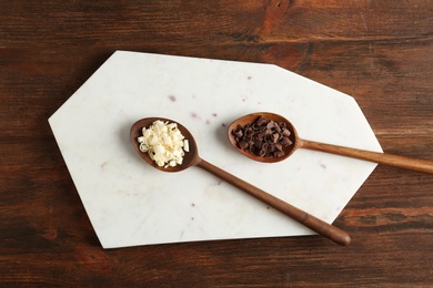 Photo of Flat lay composition with spoons of different chocolate curls on wooden background