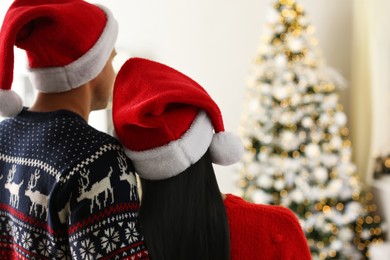 Couple in Santa hats at home, back view. Christmas celebration