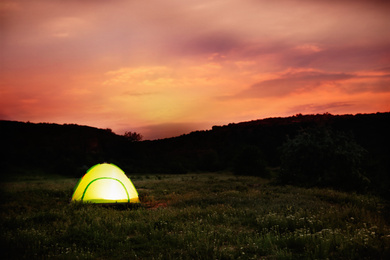 Small camping tent glowing in twilight, outdoors