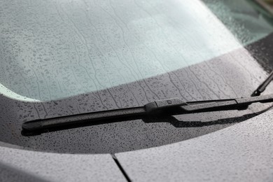 Photo of Car wiper cleaning water drops from windshield glass, closeup