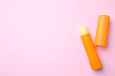 Photo of Hygienic lipsticks on pink background, flat lay. Space for text