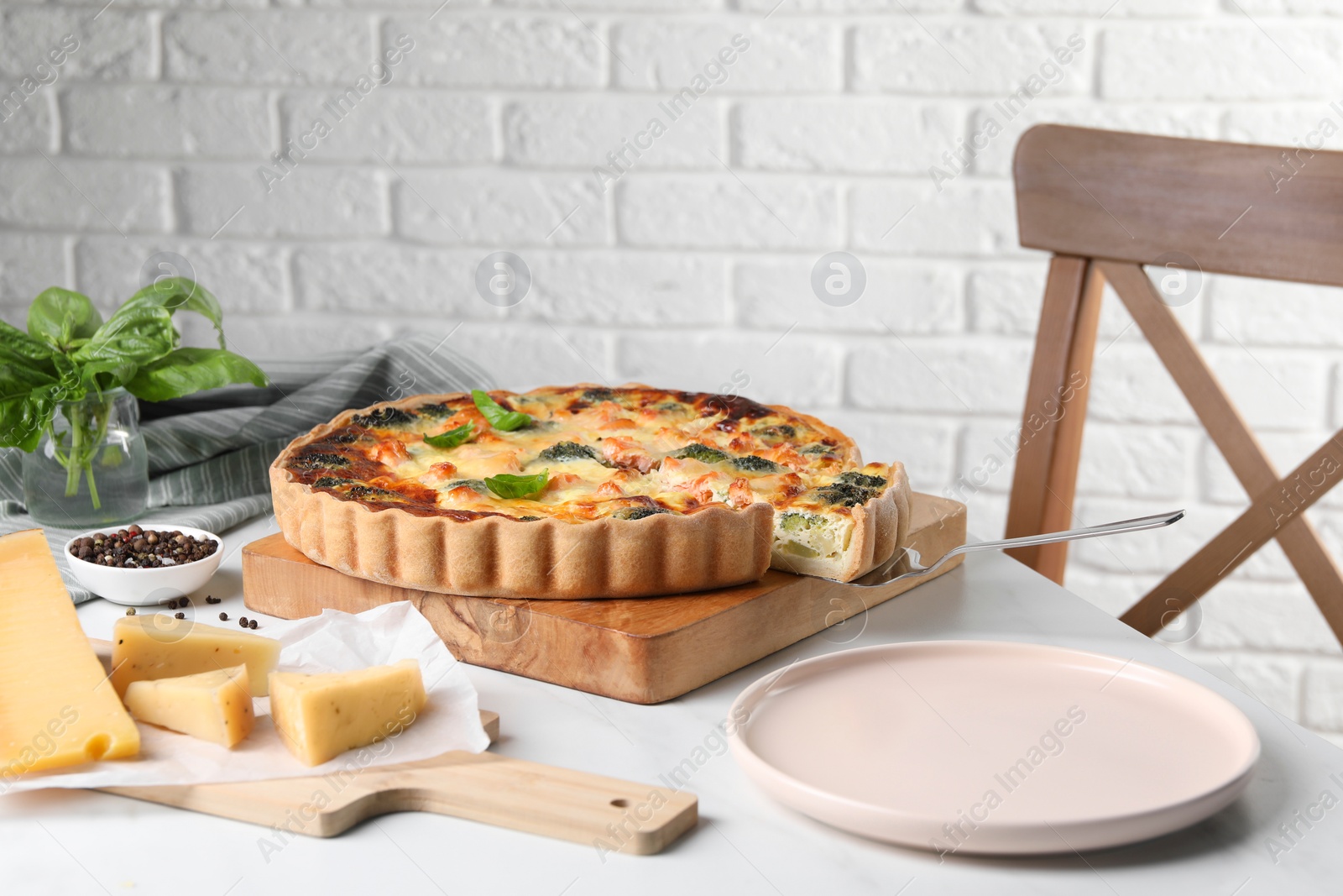 Photo of Delicious homemade quiche and ingredients on white table