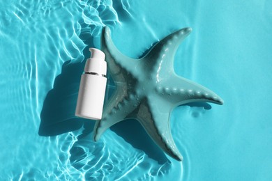 Moisturizing cream and sea star in water on light blue background, top view