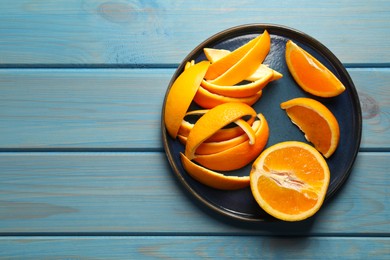 Photo of Orange peels preparing for drying and fresh fruit on light blue wooden table, top view. Space for text