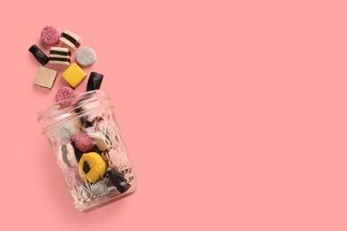 Photo of Jar with tasty liquorice candies on pink background, top view. Space for text