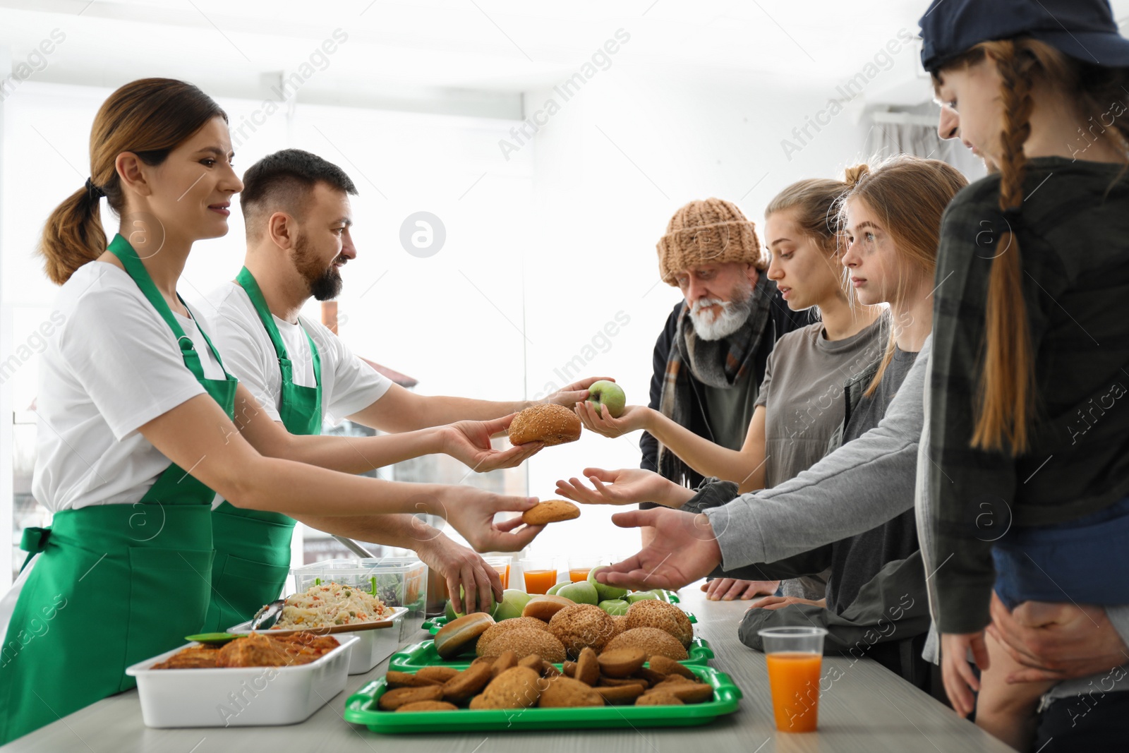 Photo of Poor people receiving food from volunteers indoors