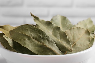 Photo of Bay leaves in white bowl, closeup view