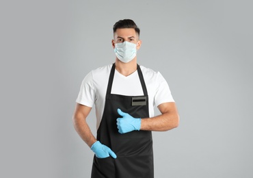 Photo of Waiter wearing medical face mask on light grey background