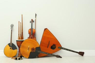 Set of different wooden musical instruments near white wall indoors