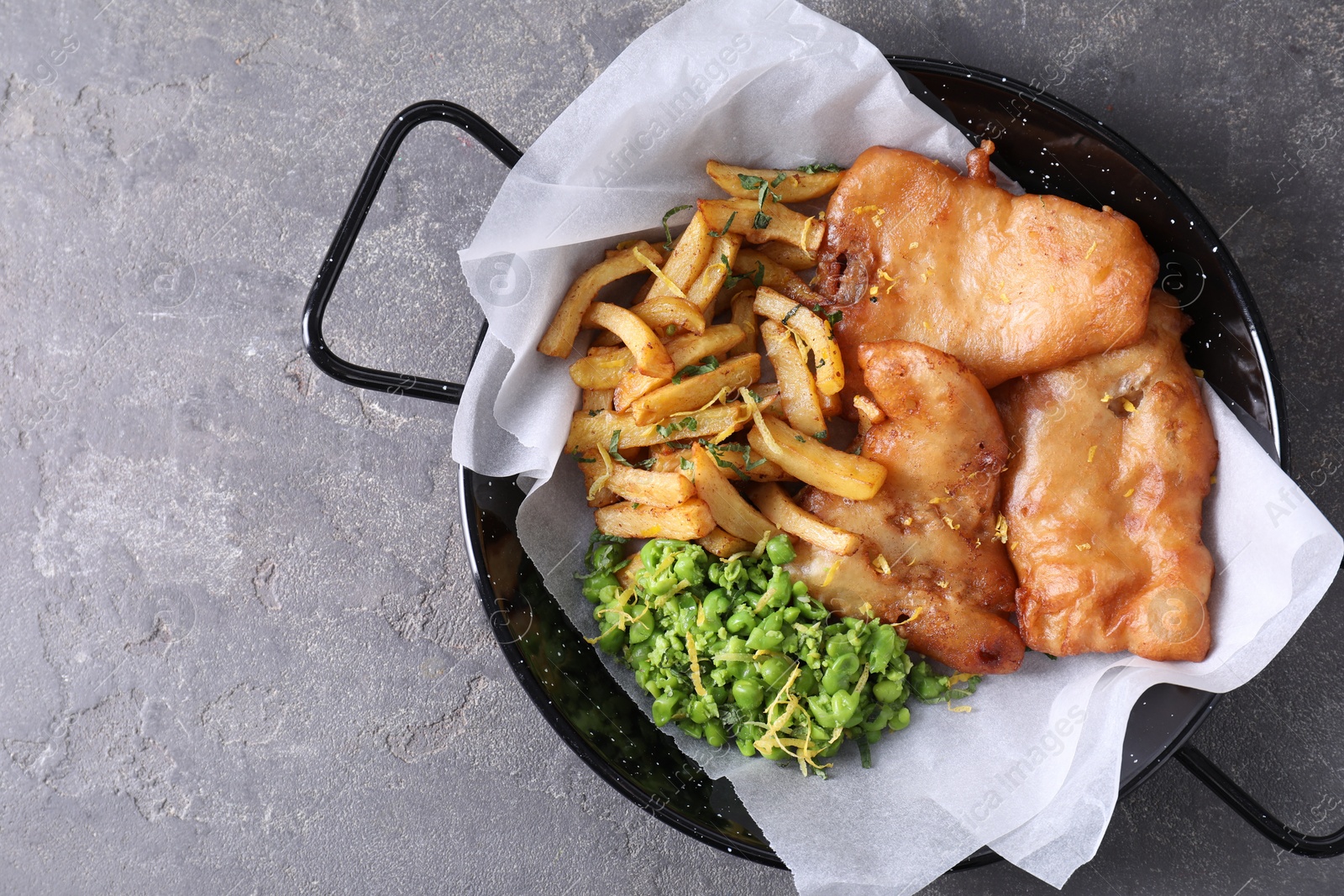 Photo of Tasty fish, chips and peas on grey table, top view. Space for text