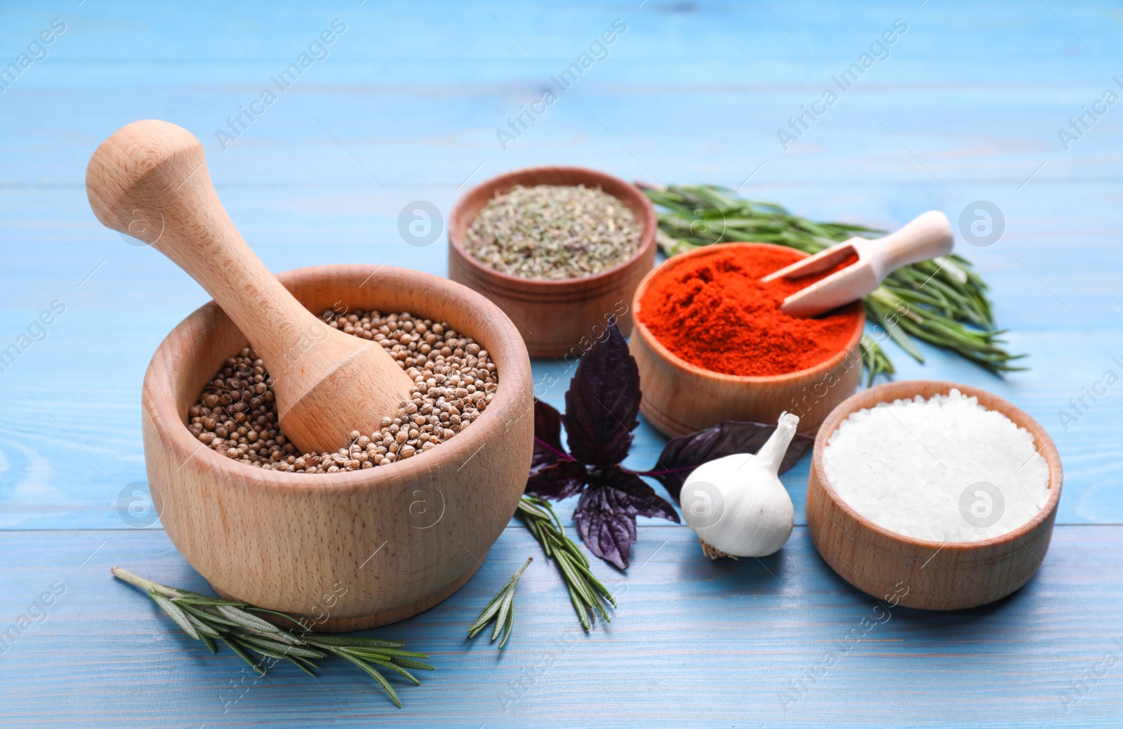 Photo of Mortar and different spices on light blue wooden table