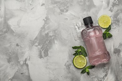 Photo of Mouthwash, mint and lime on grey marble background, flat lay. Space for text