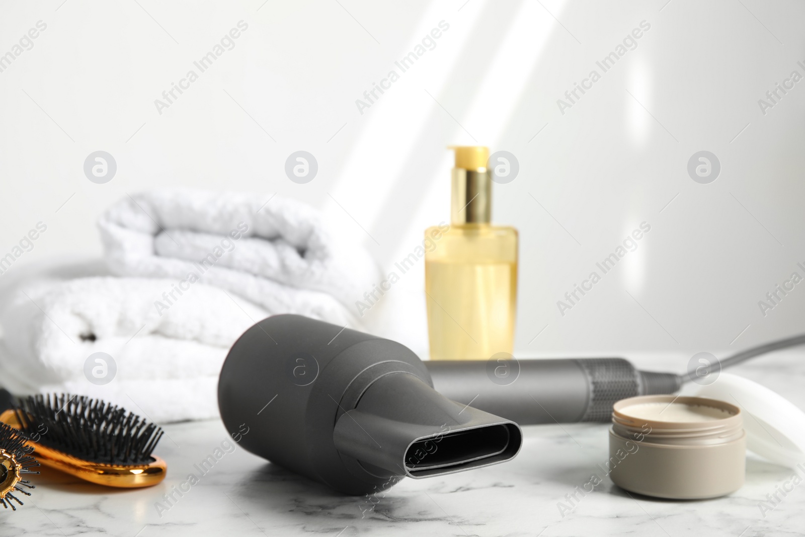 Photo of Hair care products, dryer and brush on white marble table, space for text