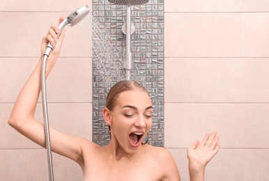 Beautiful young woman taking shower at home