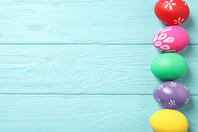 Photo of Colorful Easter eggs on light blue wooden background, flat lay. Space for text