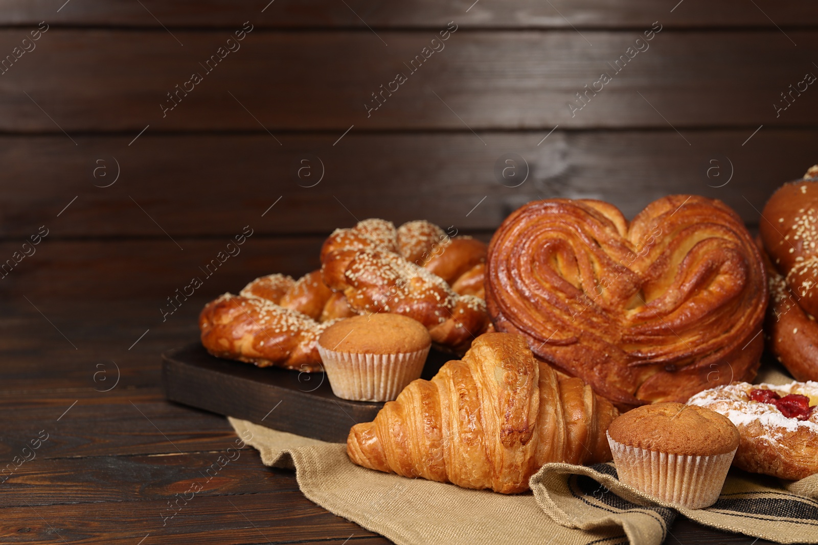 Photo of Different tasty freshly baked pastries on wooden table, space for text