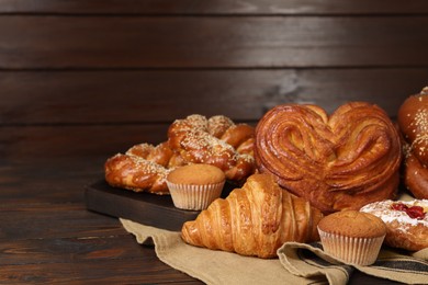 Different tasty freshly baked pastries on wooden table, space for text