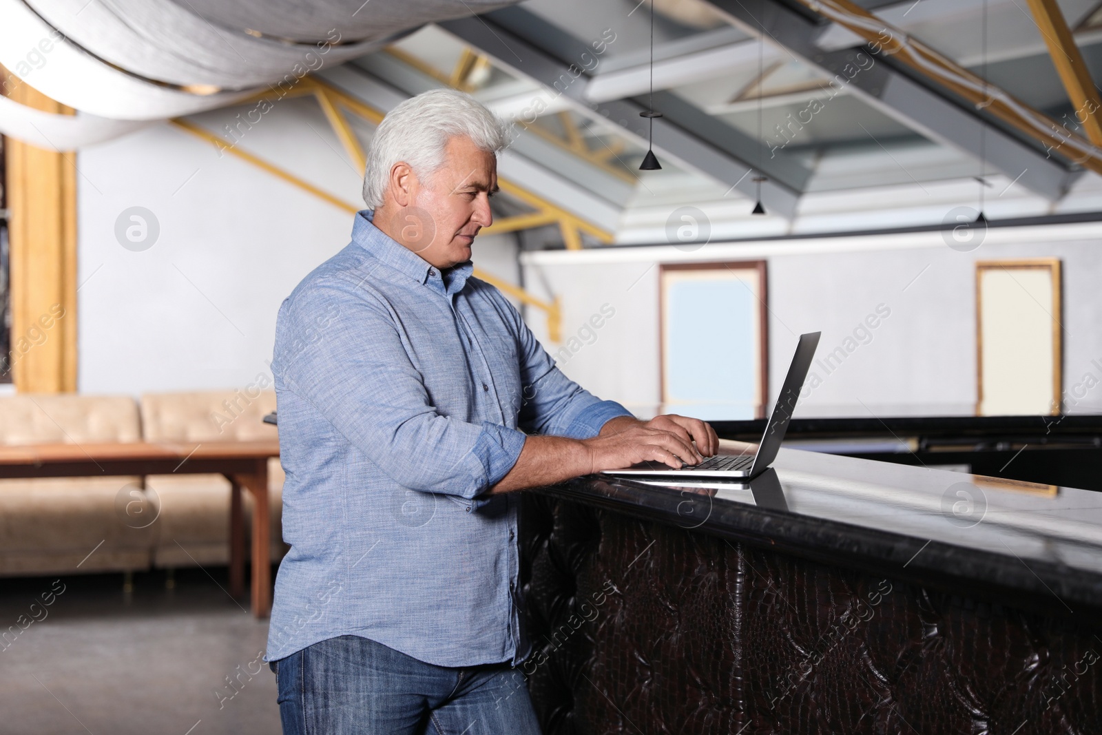 Photo of Senior business owner working with laptop in his restaurant