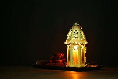 Photo of Decorative Arabic lantern and dates on table against dark background. Space for text