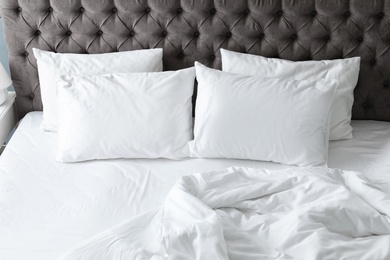 Comfortable bed with white linen and pillows at home