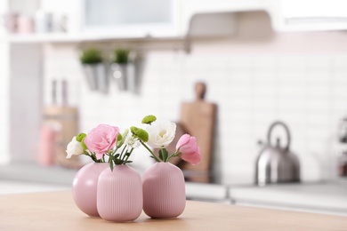 Photo of Vases with beautiful flowers on table in kitchen interior. Space for text