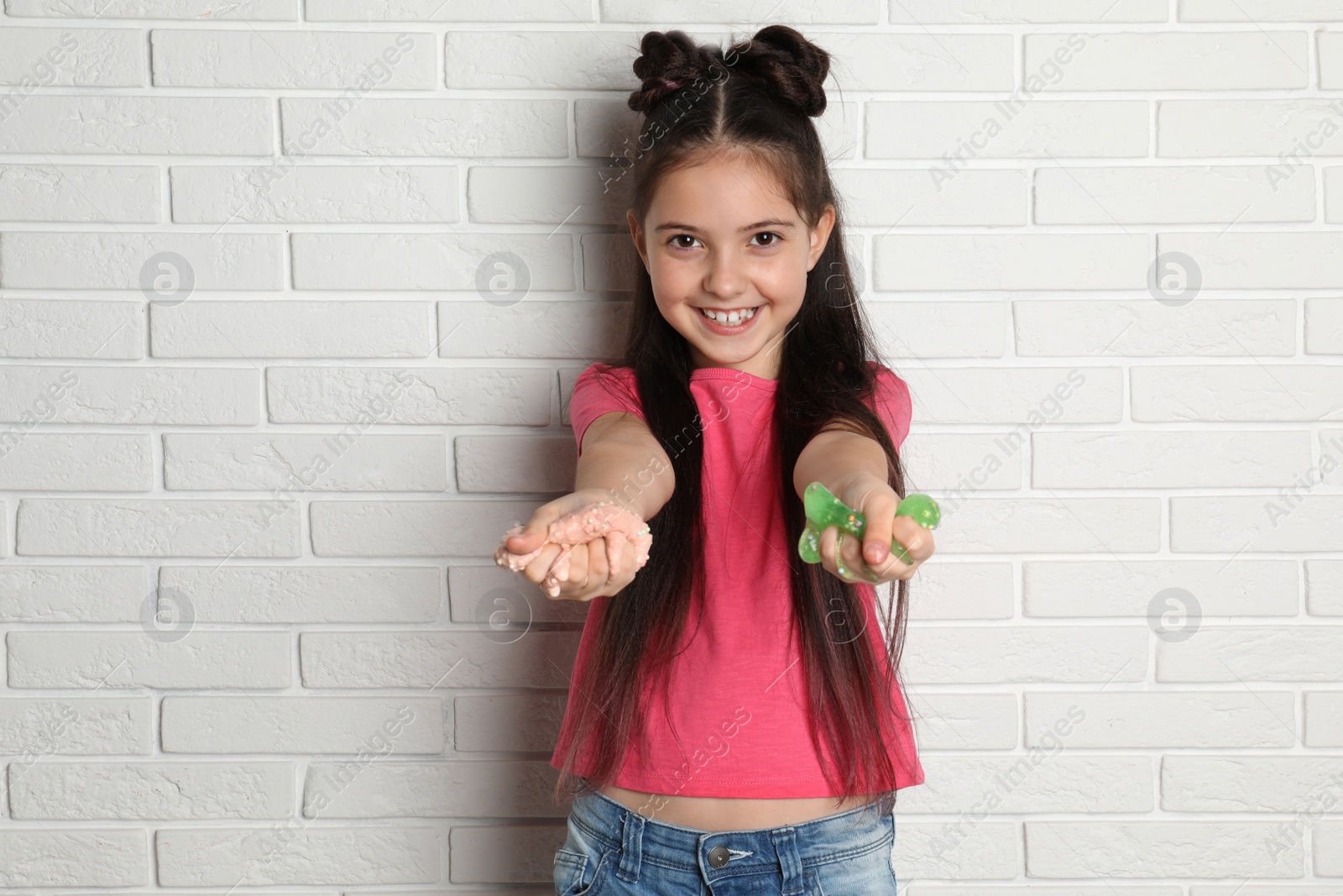 Photo of Little girl with slime near white brick wall