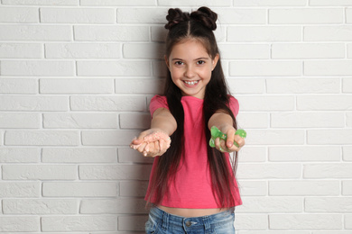 Photo of Little girl with slime near white brick wall