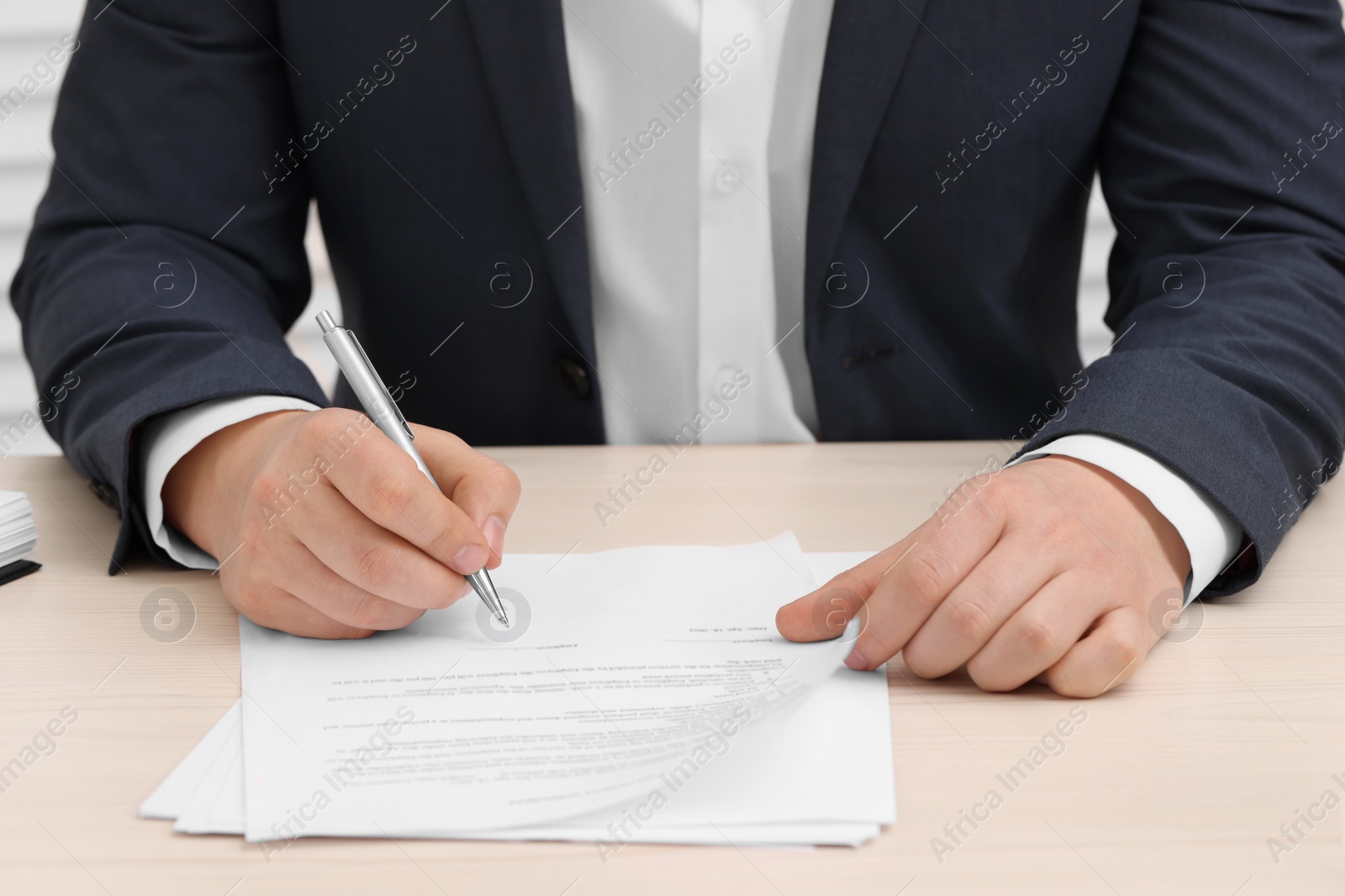 Photo of Man signing document at wooden table, closeup