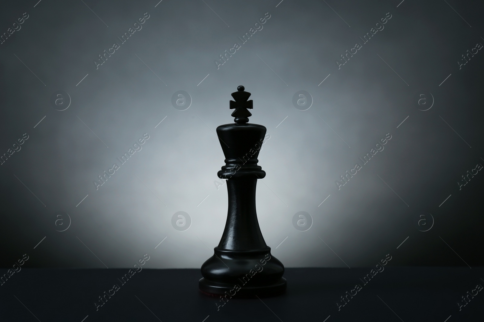 Photo of Black king on dark table against light background. Chess piece