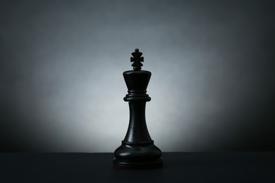 Photo of Black king on dark table against light background. Chess piece