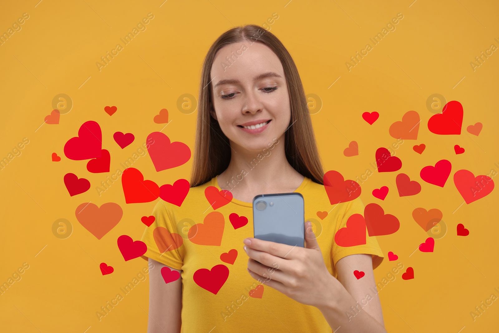 Image of Long distance love. Woman chatting with sweetheart via smartphone on golden background. Hearts flying out of device and swirling around her