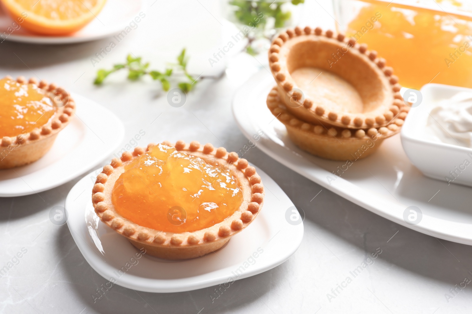 Photo of Tasty tartlets with orange jam on light background