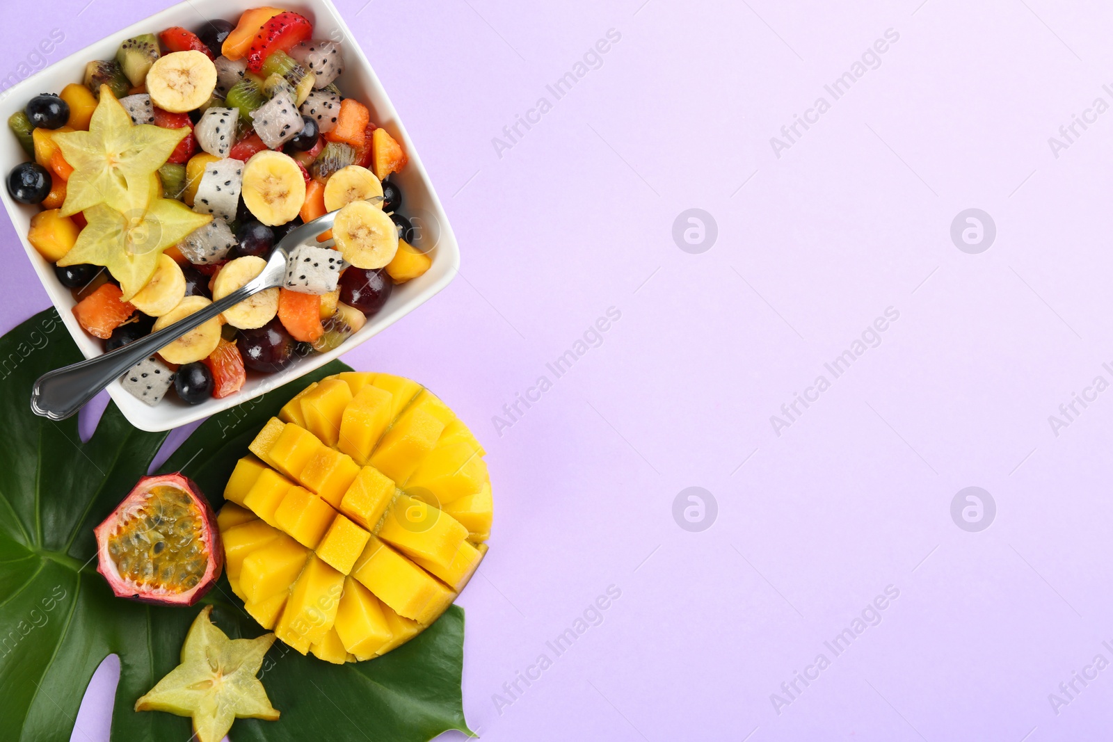 Photo of Flat lay composition with delicious exotic fruit salad on purple background. Space for text