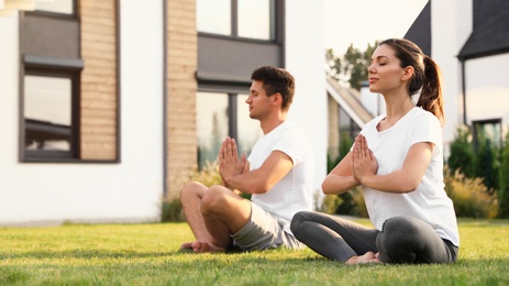 Photo of Sporty couple practicing morning yoga at backyard. Healthy lifestyle