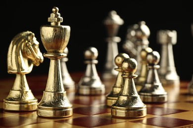 Photo of Chessboard with game pieces on black background, closeup