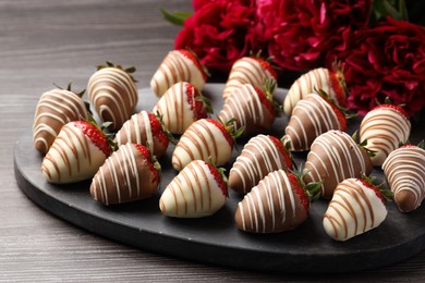 Photo of Delicious chocolate covered strawberries and flowers on wooden table, closeup