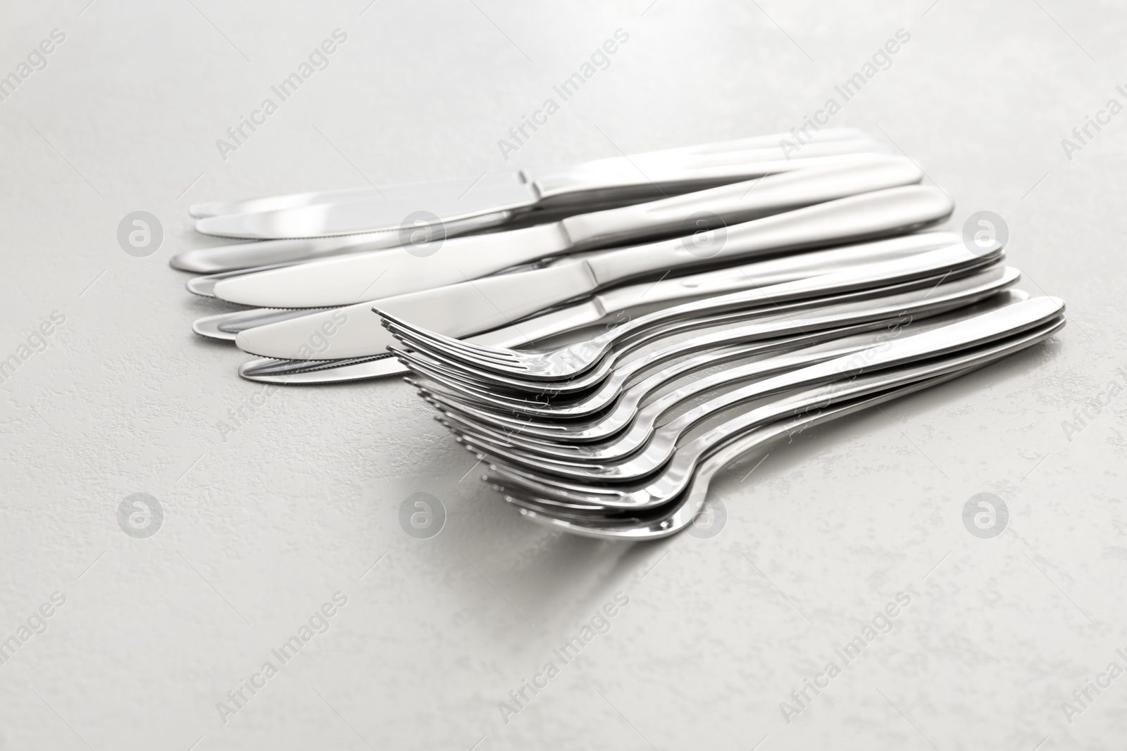 Photo of Knives and forks on white table, closeup