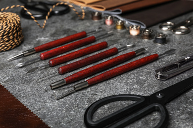 Photo of Leather samples and craftsman tools on grey stone background