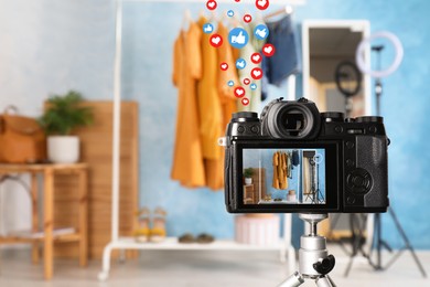 Image of Rack with stylish clothes and mirror near light blue wall indoors, focus on camera screen