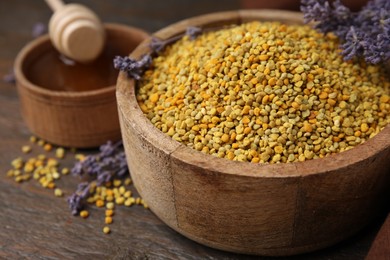 Photo of Fresh bee pollen granules and lavender on wooden table, closeup