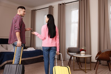 Photo of Happy couple with suitcases walking into hotel room
