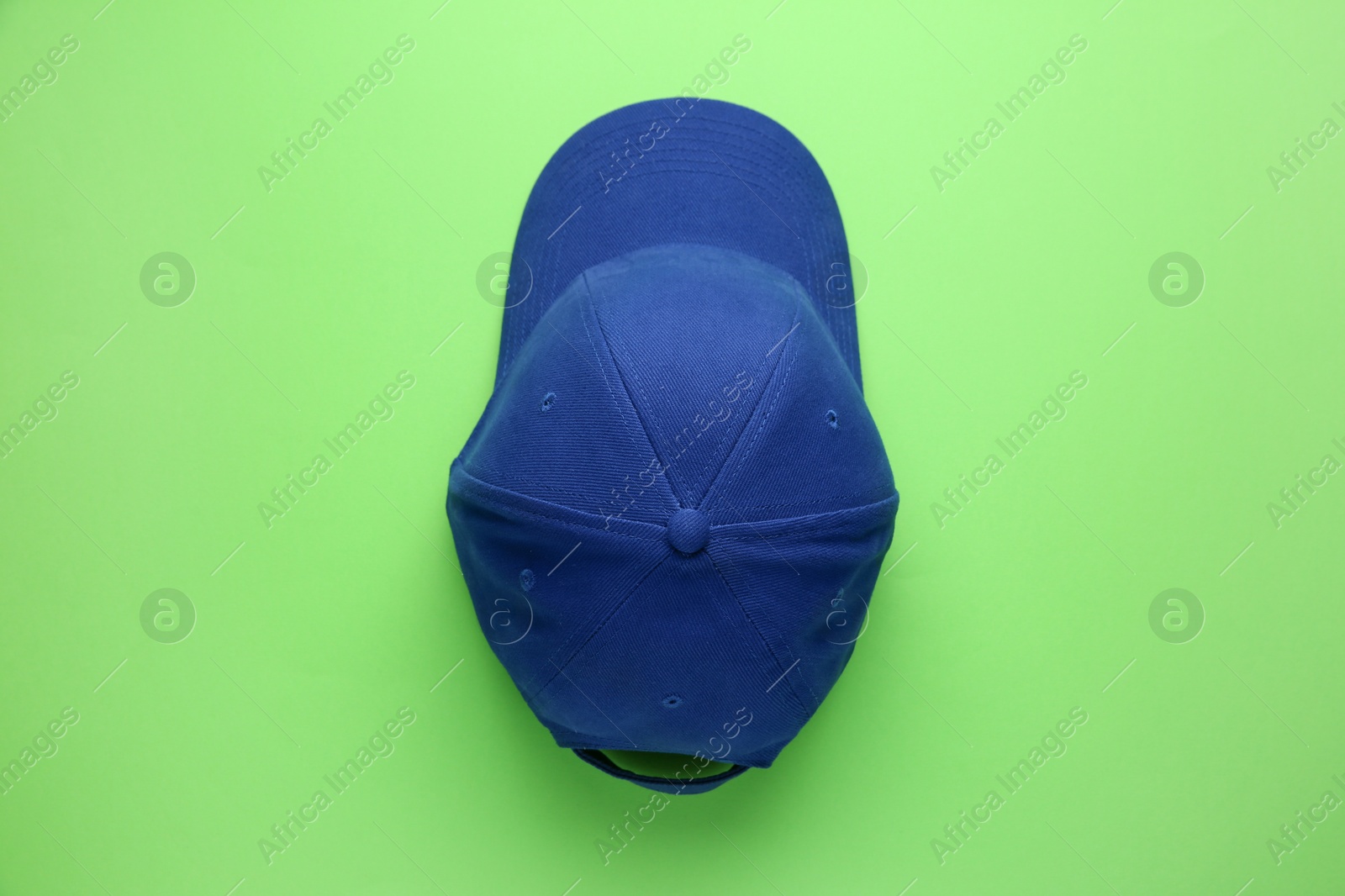 Photo of Stylish blue baseball cap on light green background, top view