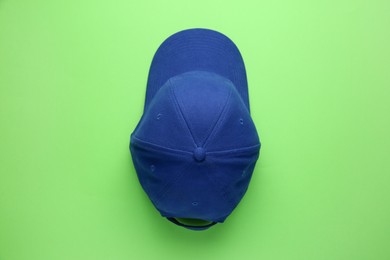 Photo of Stylish blue baseball cap on light green background, top view