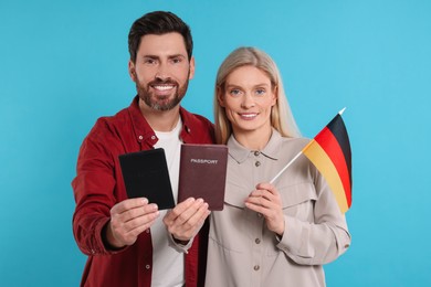 Photo of Immigration. Happy couple with passports and flag of Germany on light blue background