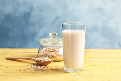 Glass with oat milk and flakes on wooden table