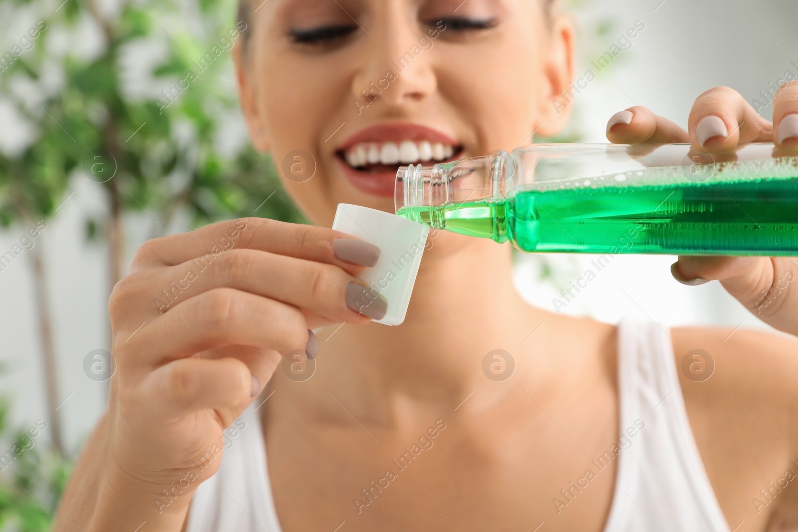 Photo of Woman pouring mouthwash from bottle into cap, closeup. Teeth care