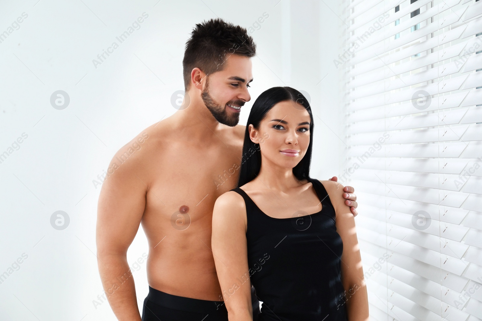 Photo of Young couple in black underwear near window indoors