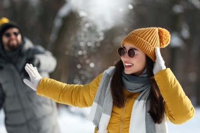 Happy couple playing snowballs on winter day outdoors