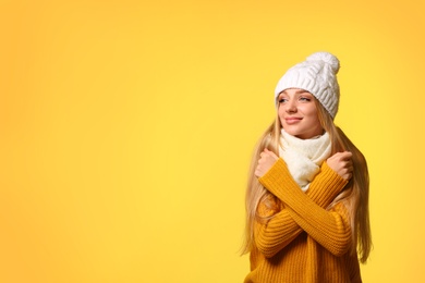 Photo of Portrait of emotional young woman in stylish hat, sweater and scarf on color background, space for text. Winter atmosphere